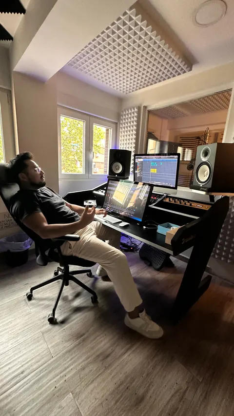 Un productor escucha una mezcla recostado en la silla del estudio
