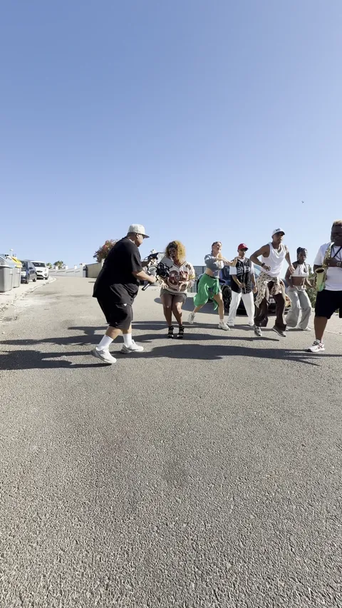 Rodaje de un videoclip en una carretera al sol: el artista baila con su grupo