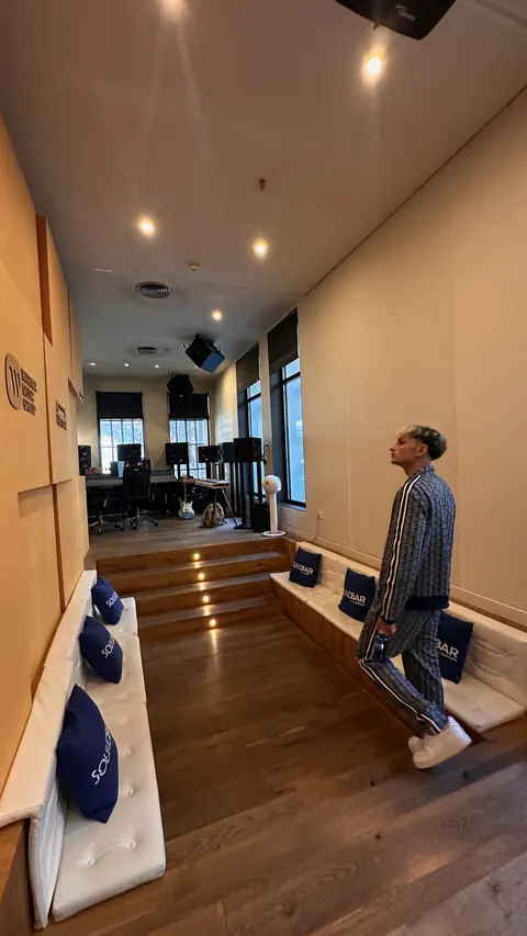 Un artista recorre un estudio de grabación con sofá y escalones