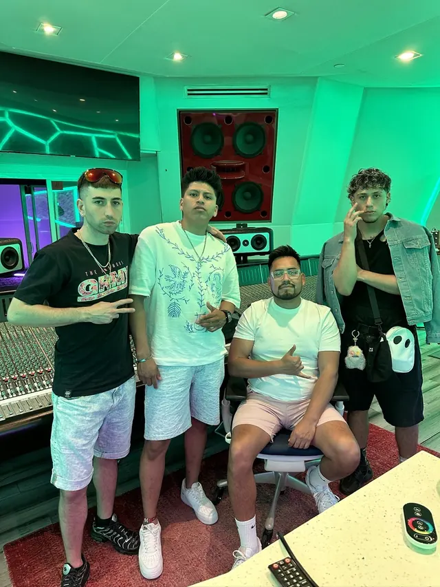 Macuto sentado en la mesa de mezclas de los estudios Rebel11 de Miami, con tres artistas