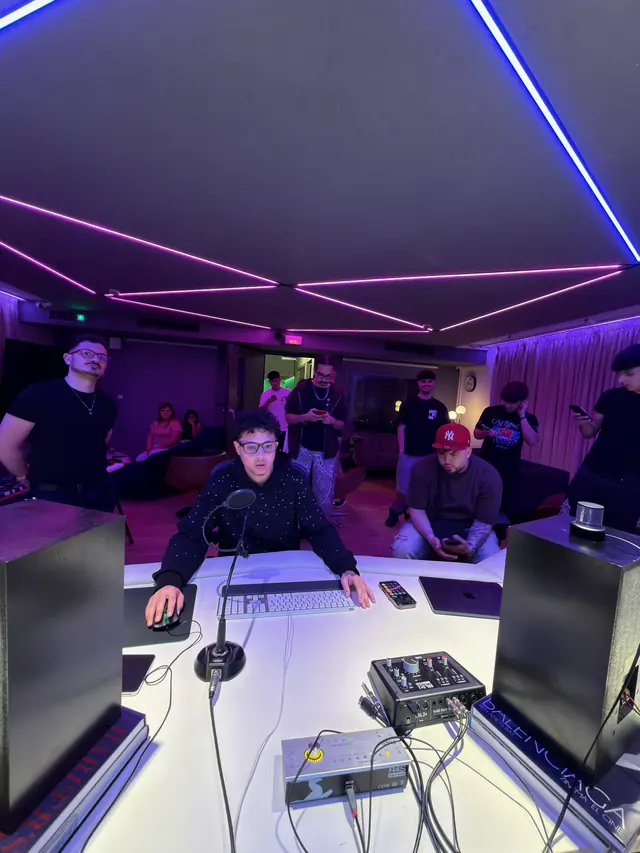 El estudio con luces moradas y artistas alrededor de la mesa de mezclas