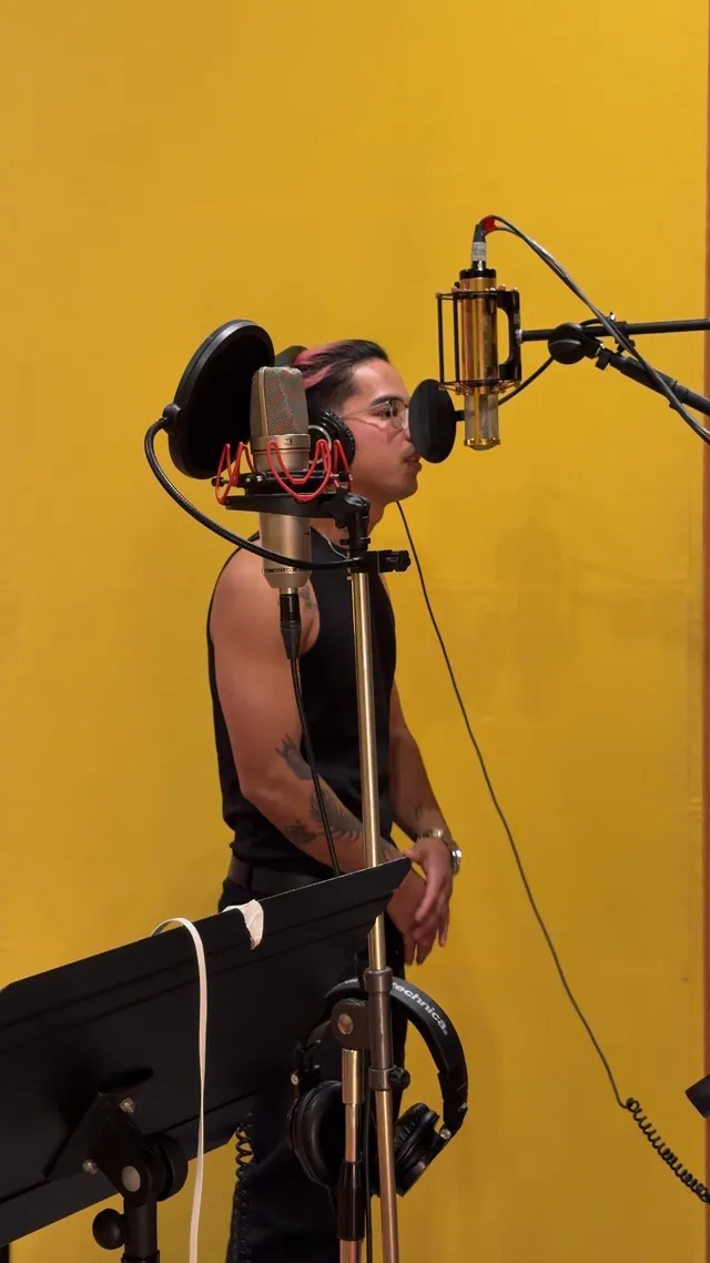 Un artista del DAP canta en la cabina de grabación de fondo amarillo