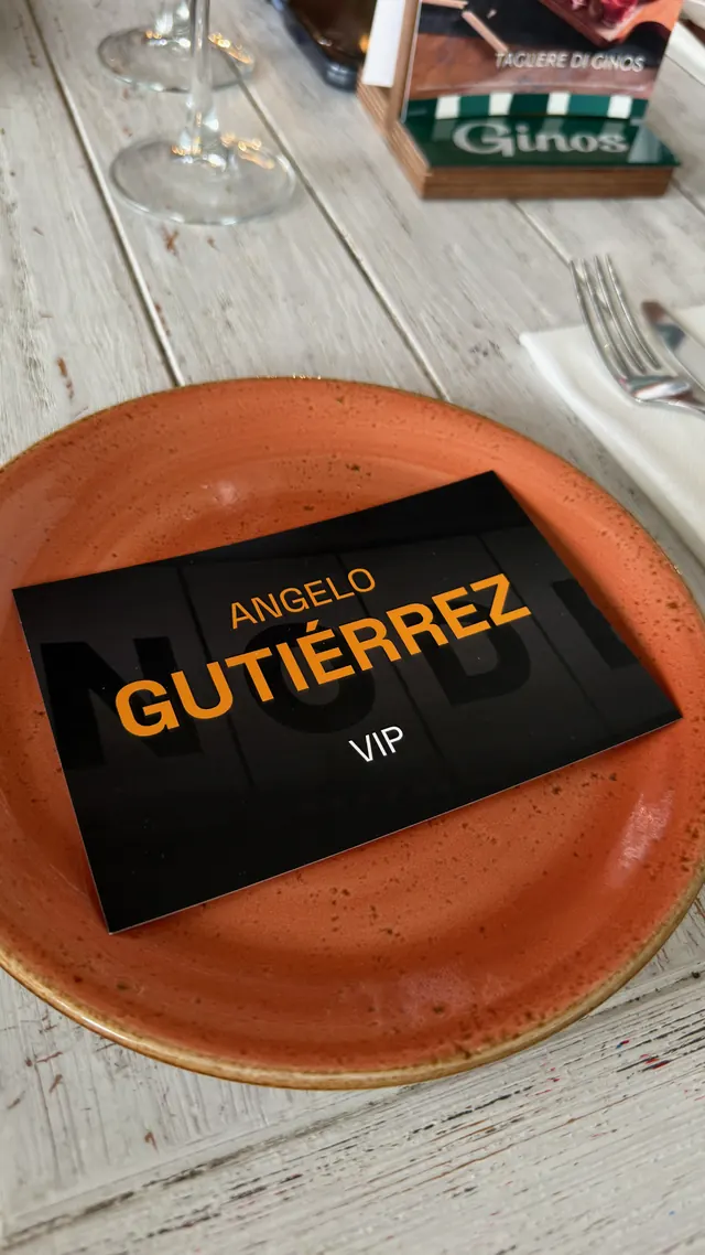 Tarjeta VIP de NODE 2026 a nombre de Angelo Gutiérrez sobre un plato