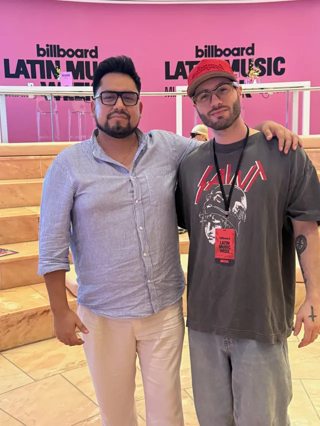 Macuto con un asistente de la semana ante el muro rosa de Billboard Latin Music Week